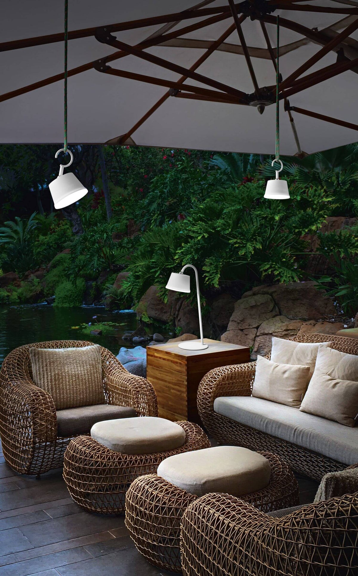 Mise en ambiance extérieure sous parasol, suspensions et lampe de table avec mobilier.