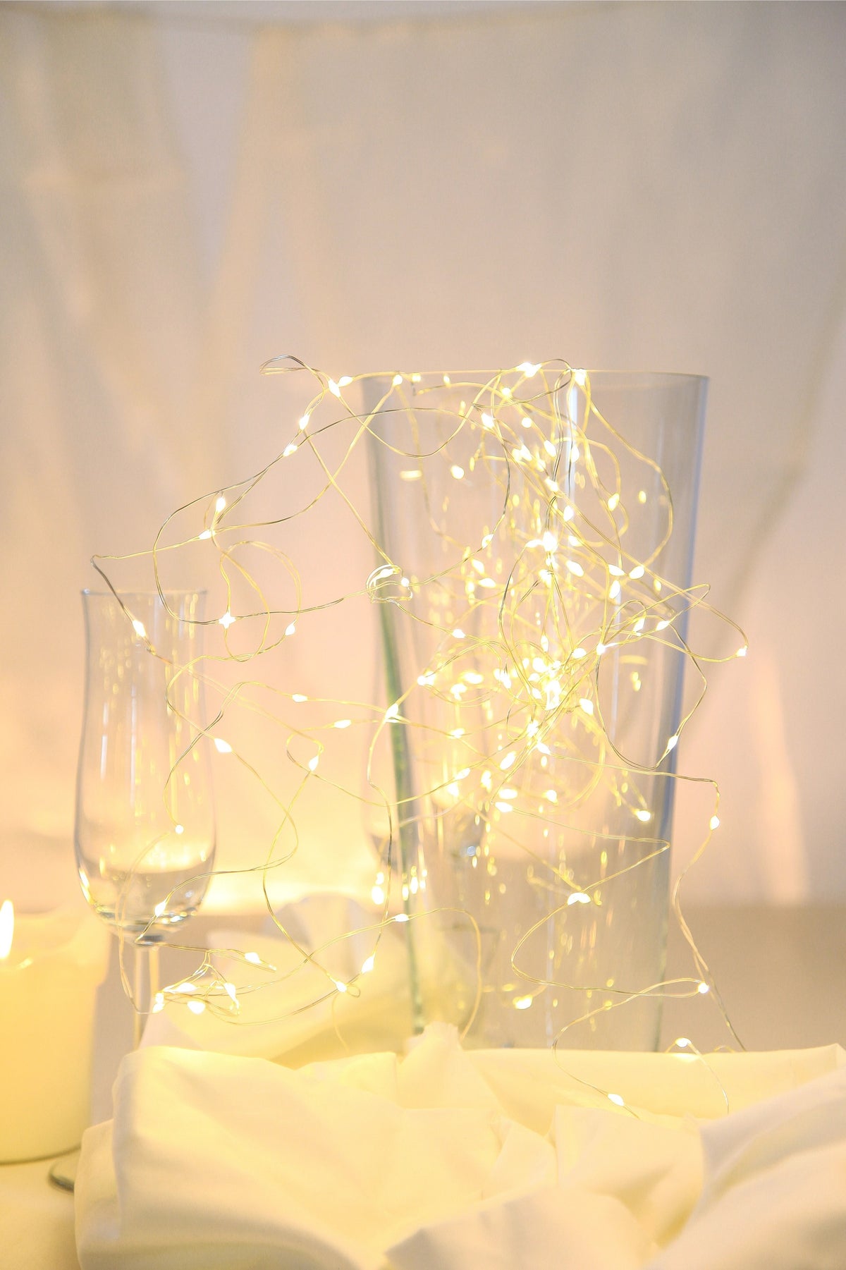 Guirlande lumineuse posée autour d'un vase en verre sur une table dressée