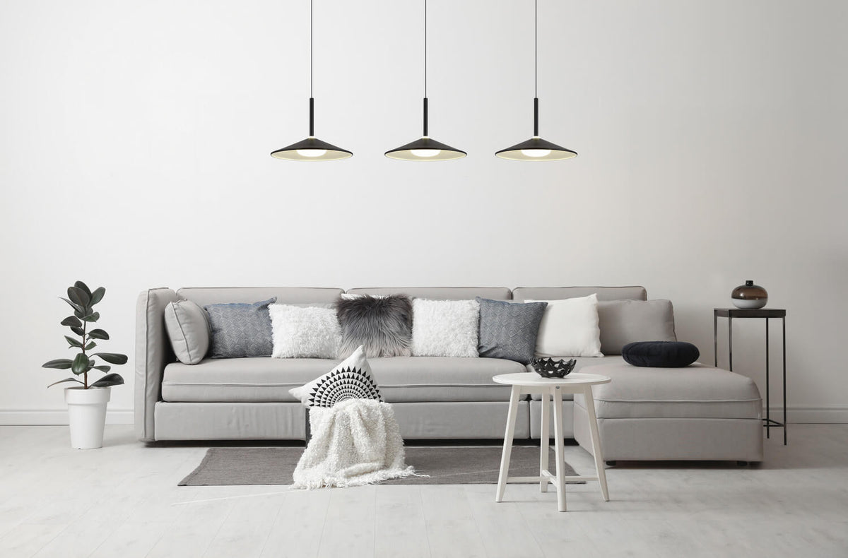 Mise en ambiance dans un salon clair avec canapé gris et suspension à trois points