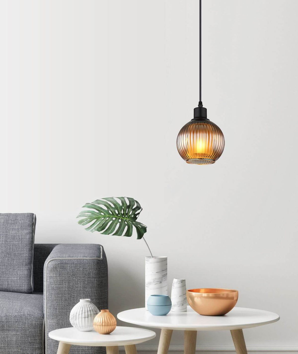 Mise en ambiance dans un salon moderne, suspension allumée au-dessus d'une table basse.