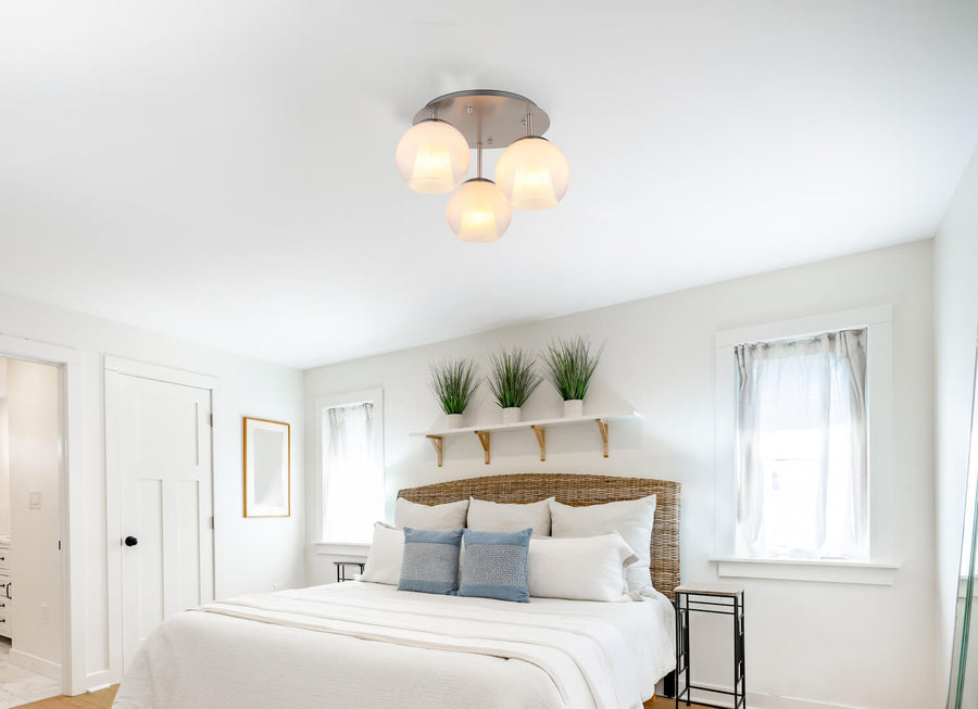 Plafonnier allumé au-dessus d'un lit dans une chambre blanche avec étagère et plantes