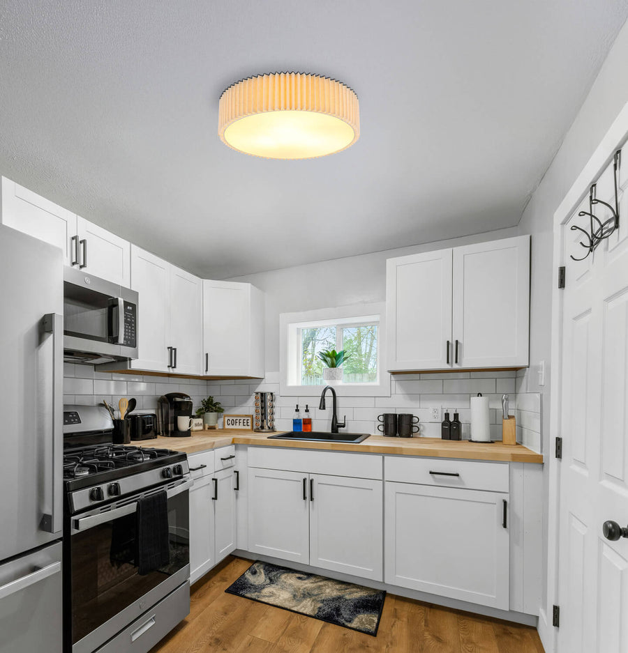Plafonnier allumé installé au plafond d'une cuisine blanche et bois.
