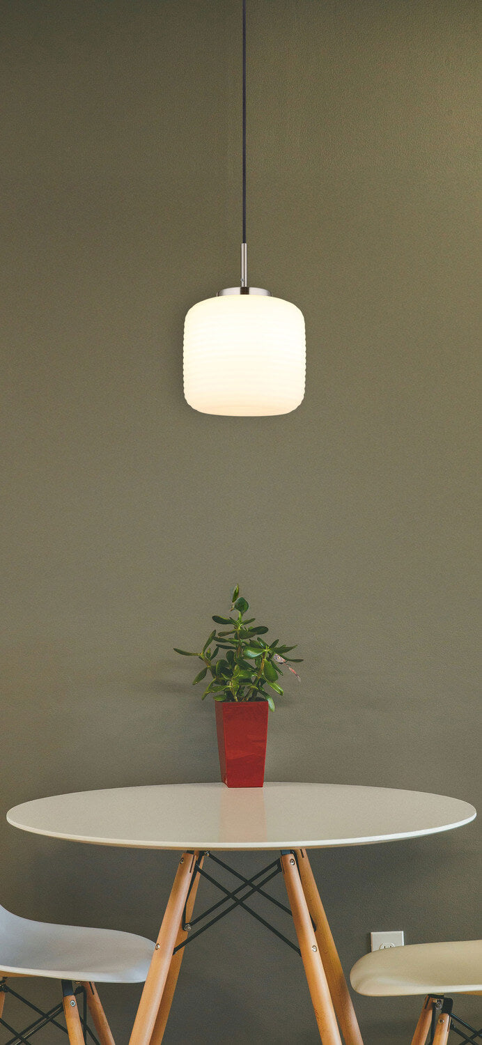 Mise en ambiance au-dessus d'une table ronde en bois, suspension allumée devant un mur olive