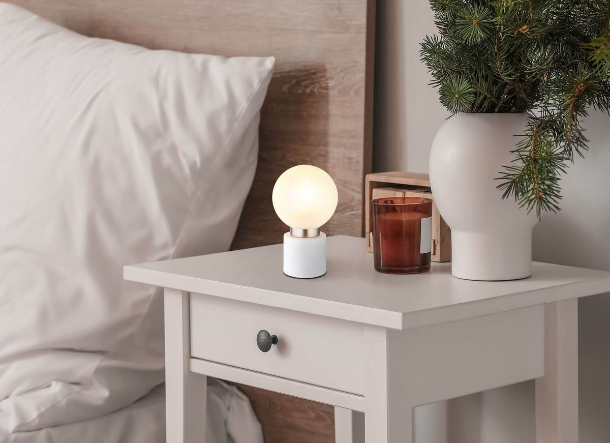 Lampe allumée posée sur une table de chevet, ambiance de chambre