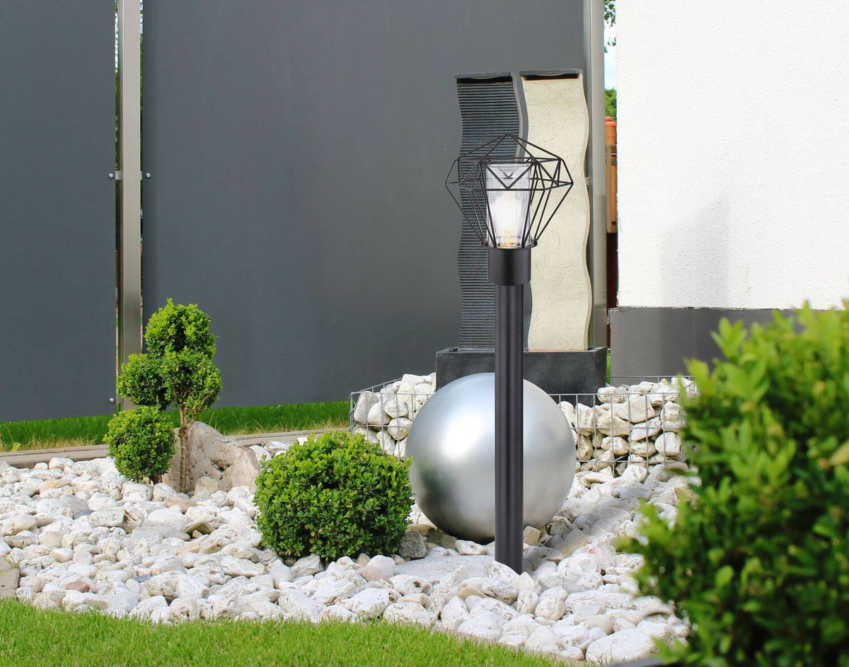 Mise en ambiance extérieure, luminaire planté dans gravier, haie et boule décorative