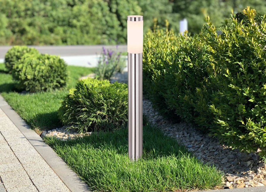 Borne lumineuse en inox installée en bordure de gazon et de graviers décoratifs.