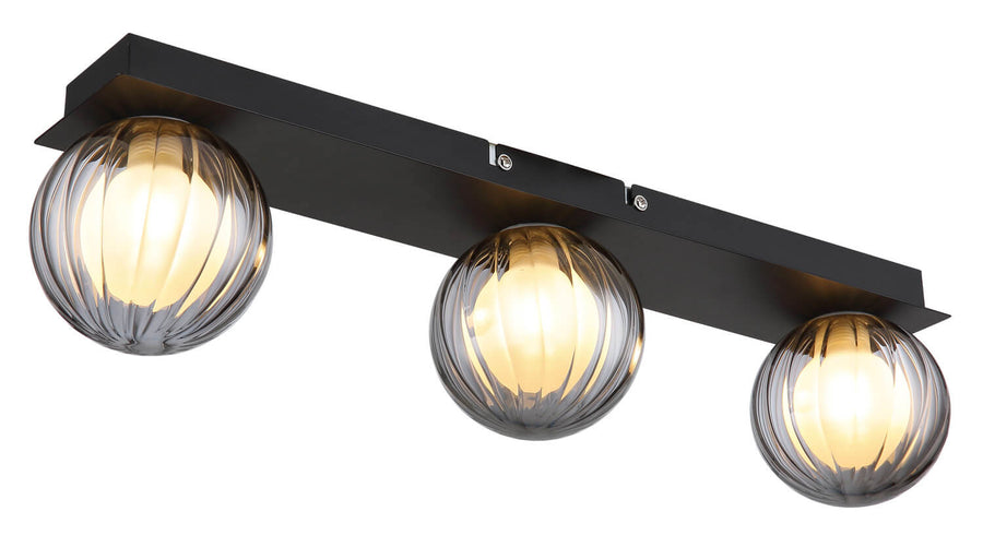 Détail du plafonnier avec ses trois globes en verre cannelé et sa base rectangulaire noire.