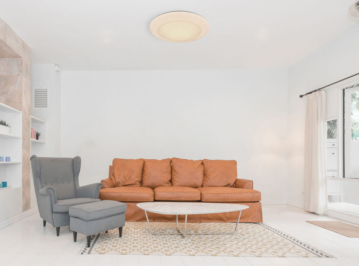 Mise en ambiance dans un salon blanc, plafonnier rond éclairé fixé au plafond