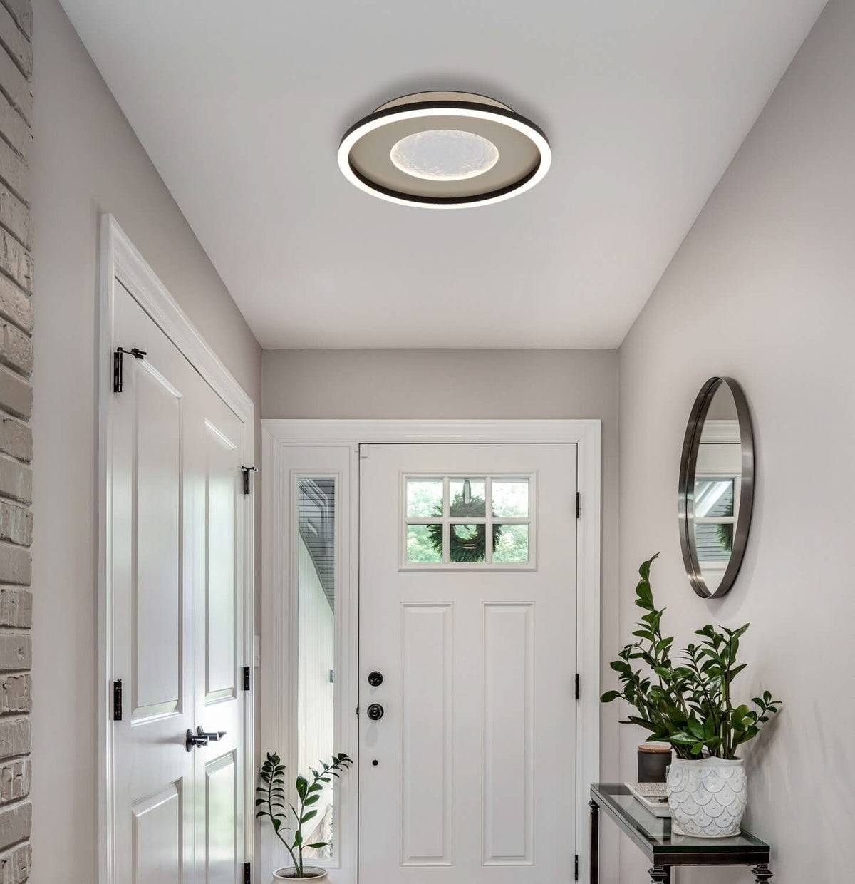 Mise en ambiance du plafonnier dans une entrée, au-dessus d'une porte blanche vitrée.