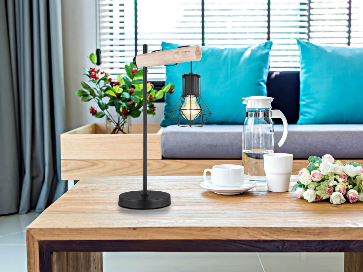 Mise en ambiance sur table basse en bois, avec canapé, coussins bleus et tasses.