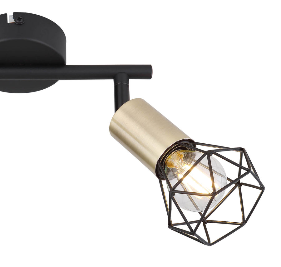 Détail d'une tête orientable : douille dorée, cage géométrique et ampoule allumée.