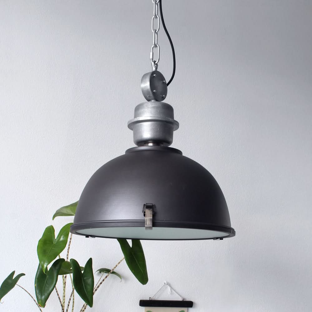 Suspension industrielle noire Bikkel en ambiance salon avec plante