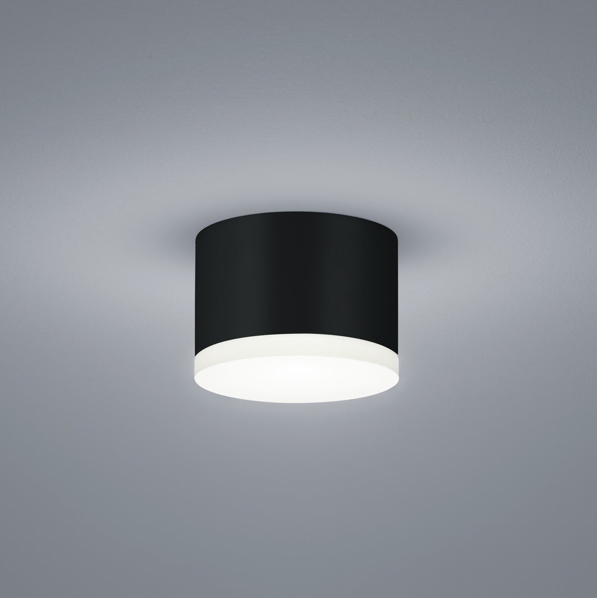 Plafonnier cylindrique noir vu de face sur fond gris clair, diffuseur blanc opalin.