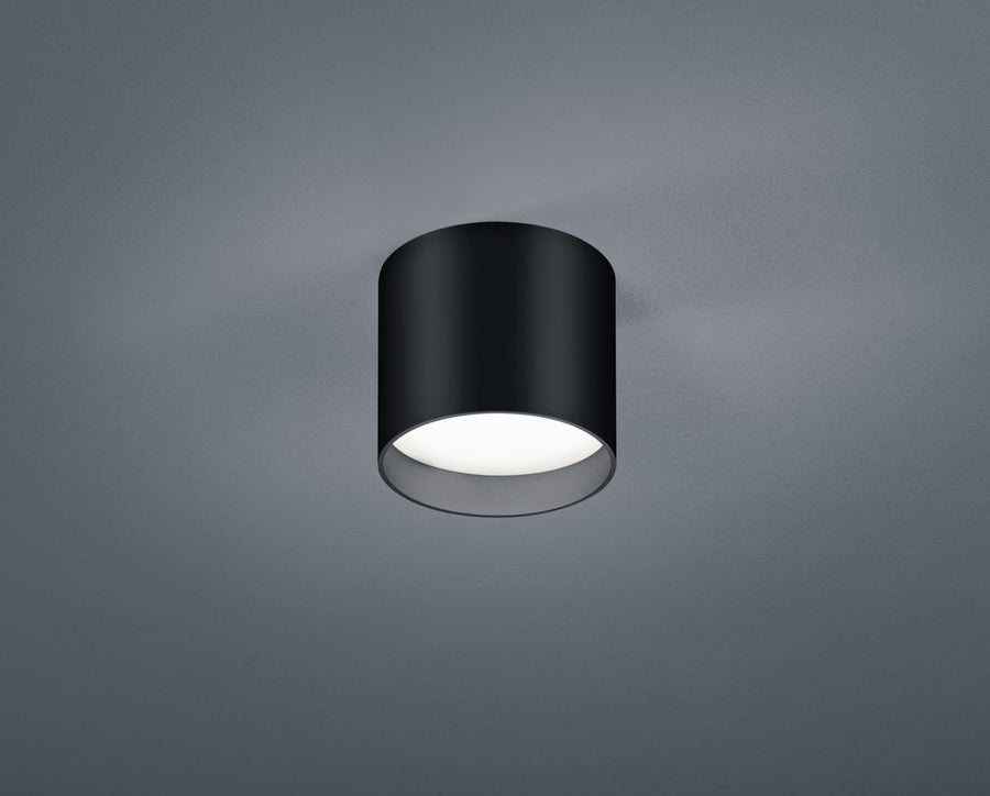 Plafonnier cylindrique noir vu de face sur fond gris, finition mate