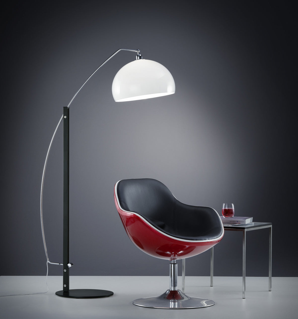 Vue de trois-quarts du lampadaire arc allumé près d'un fauteuil rouge