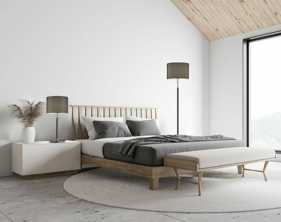 Ambiance de chambre épurée montrant la lampe allumée près du lit, style scandinave.