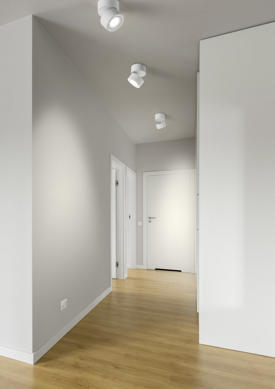 Trois spots blancs fixés au plafond éclairant un couloir vide