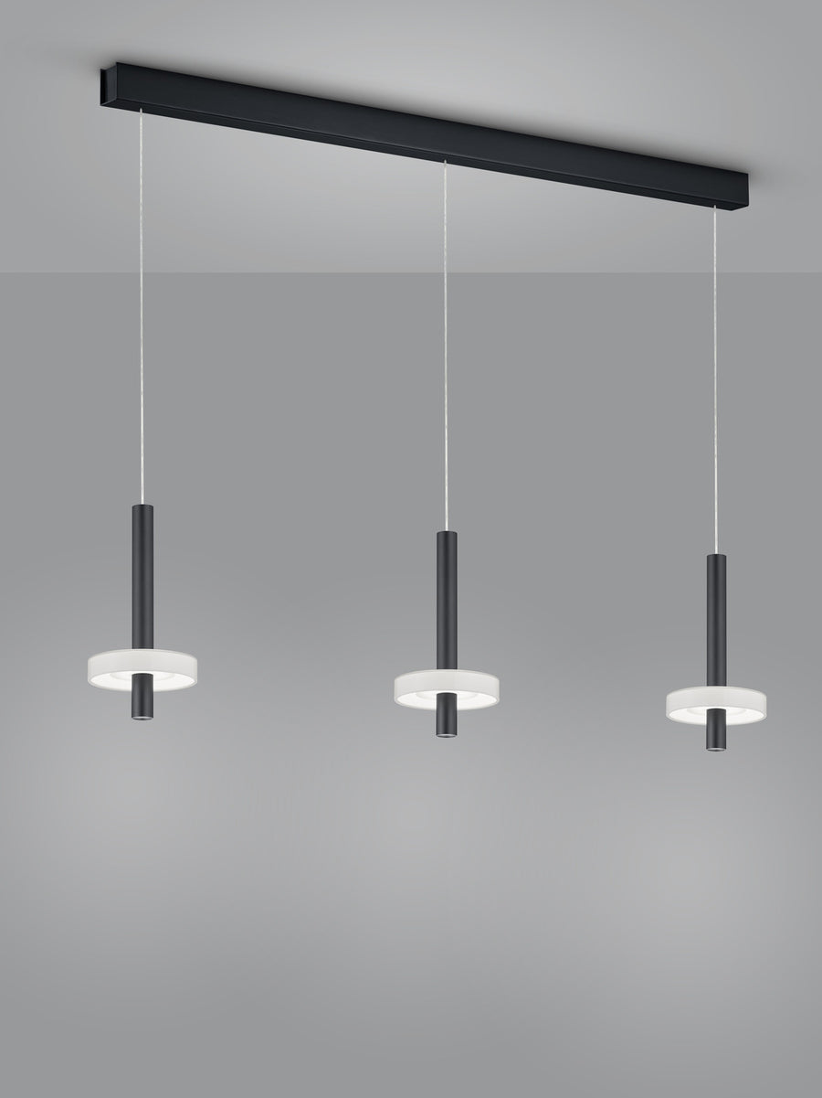 Détail rapproché des trois cylindres noirs et de leurs anneaux lumineux blancs.