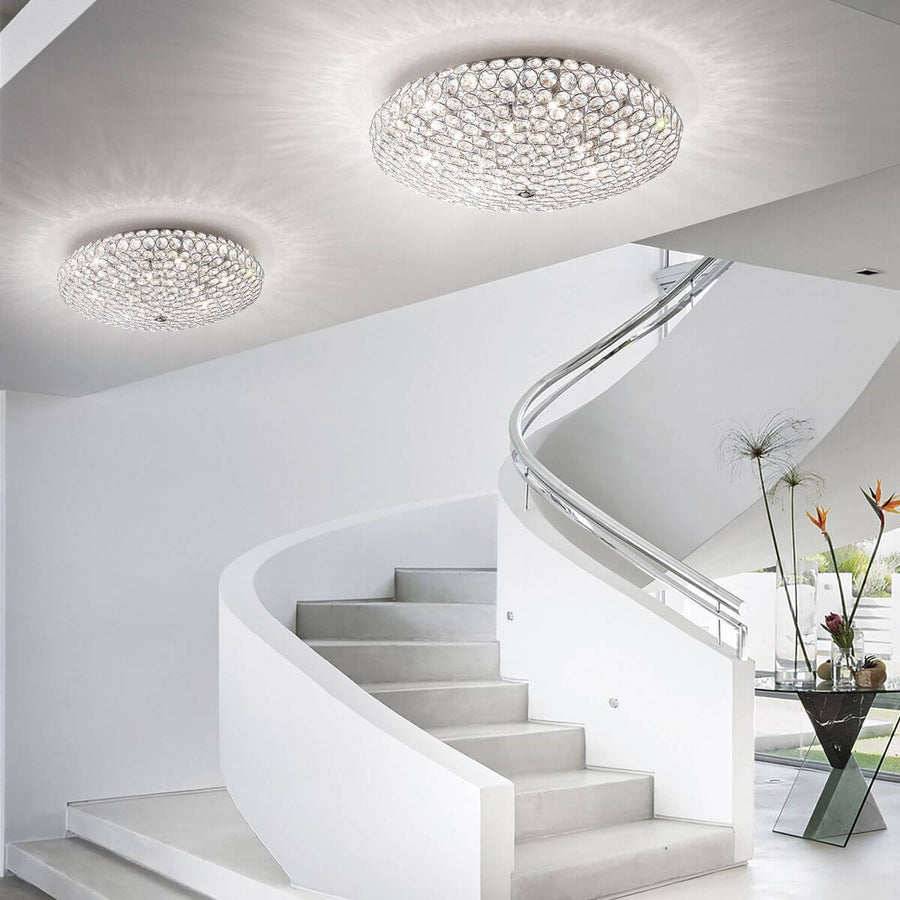 Deux plafonniers cristal éclairant le plafond blanc au-dessus d'un escalier courbe