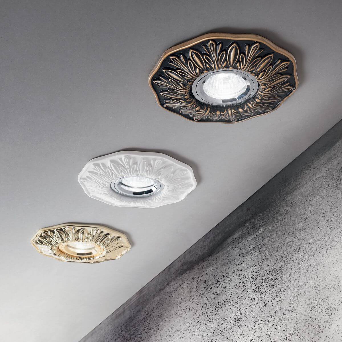 Mise en ambiance de trois spots encastrés au plafond, finitions dorée, blanche et laiton
