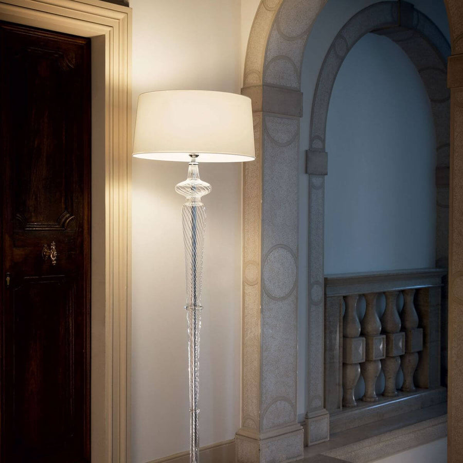 Lampadaire allumé dans une entrée, près d'une porte et d'une arche en pierre.