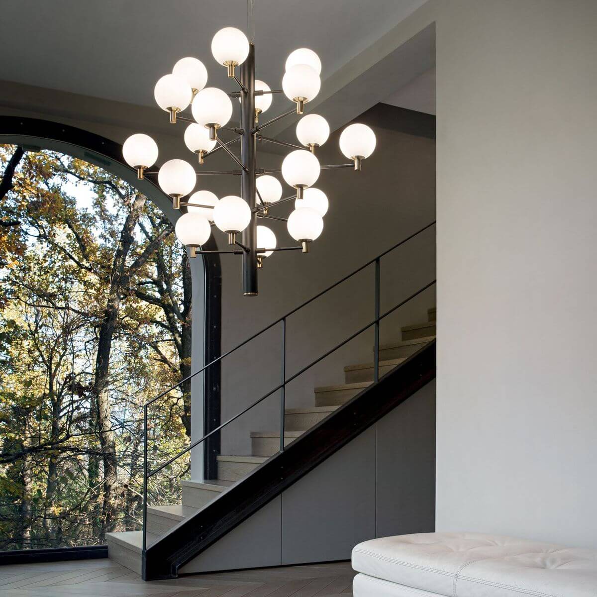 Luminaire suspendu en mise en ambiance dans un escalier, près d'une grande baie vitrée.