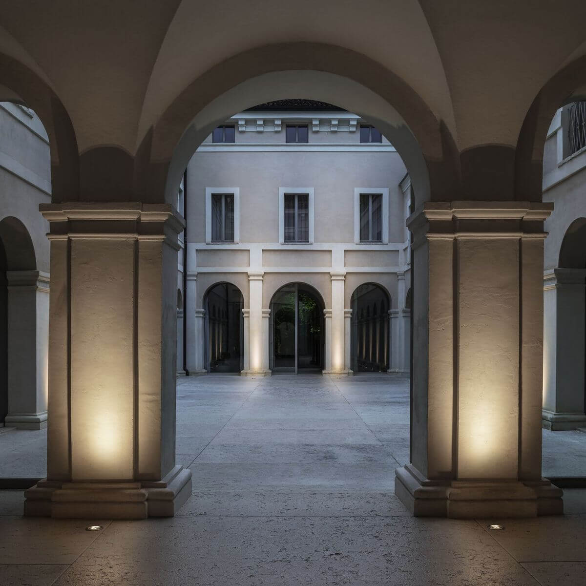 Mise en ambiance nocturne de colonnes éclairées par des luminaires encastrés au sol.