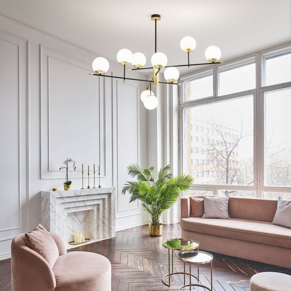 Le luminaire suspendu éclaire un salon contemporain avec canapé rose et cheminée en marbre.
