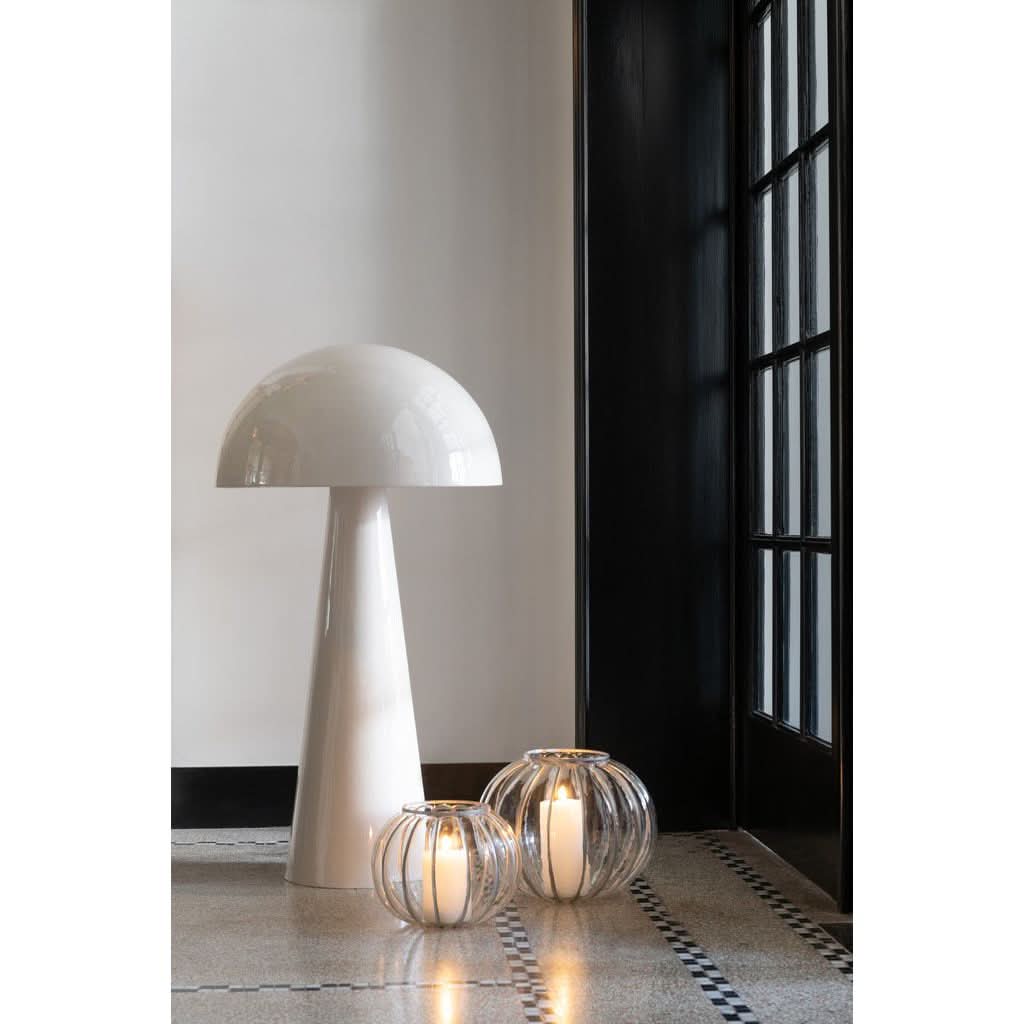 Lampe posée au sol près d'une porte vitrée noire, lanternes à bougies allumées