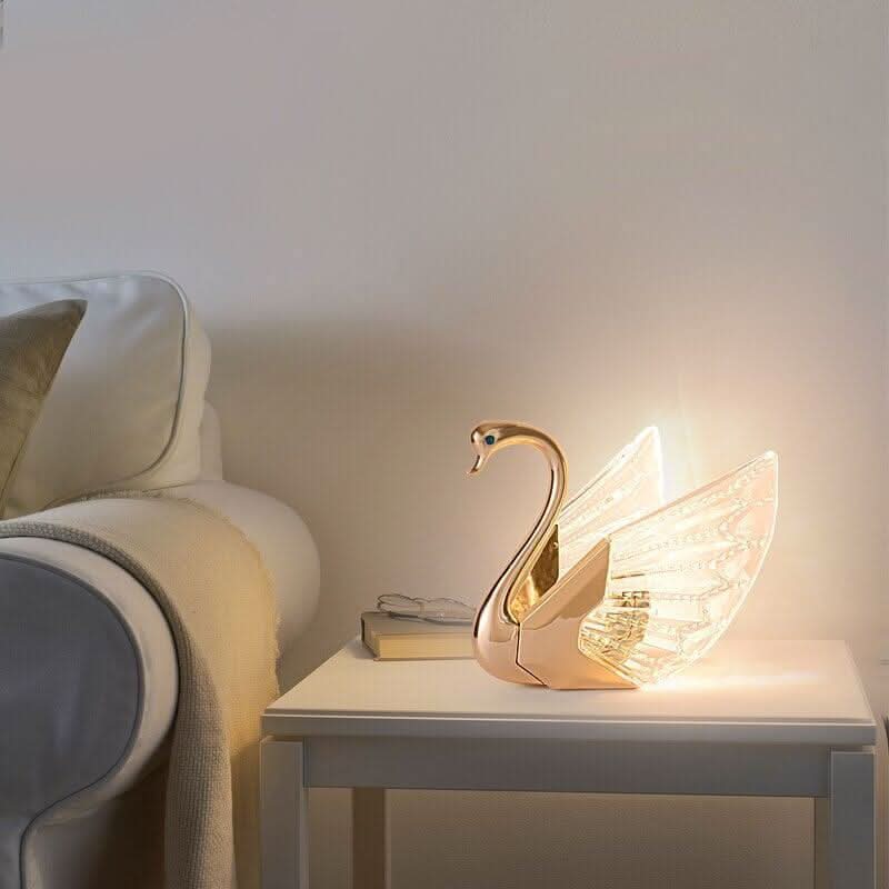 Lampe cygne allumée sur une table de chevet près d'un lit blanc