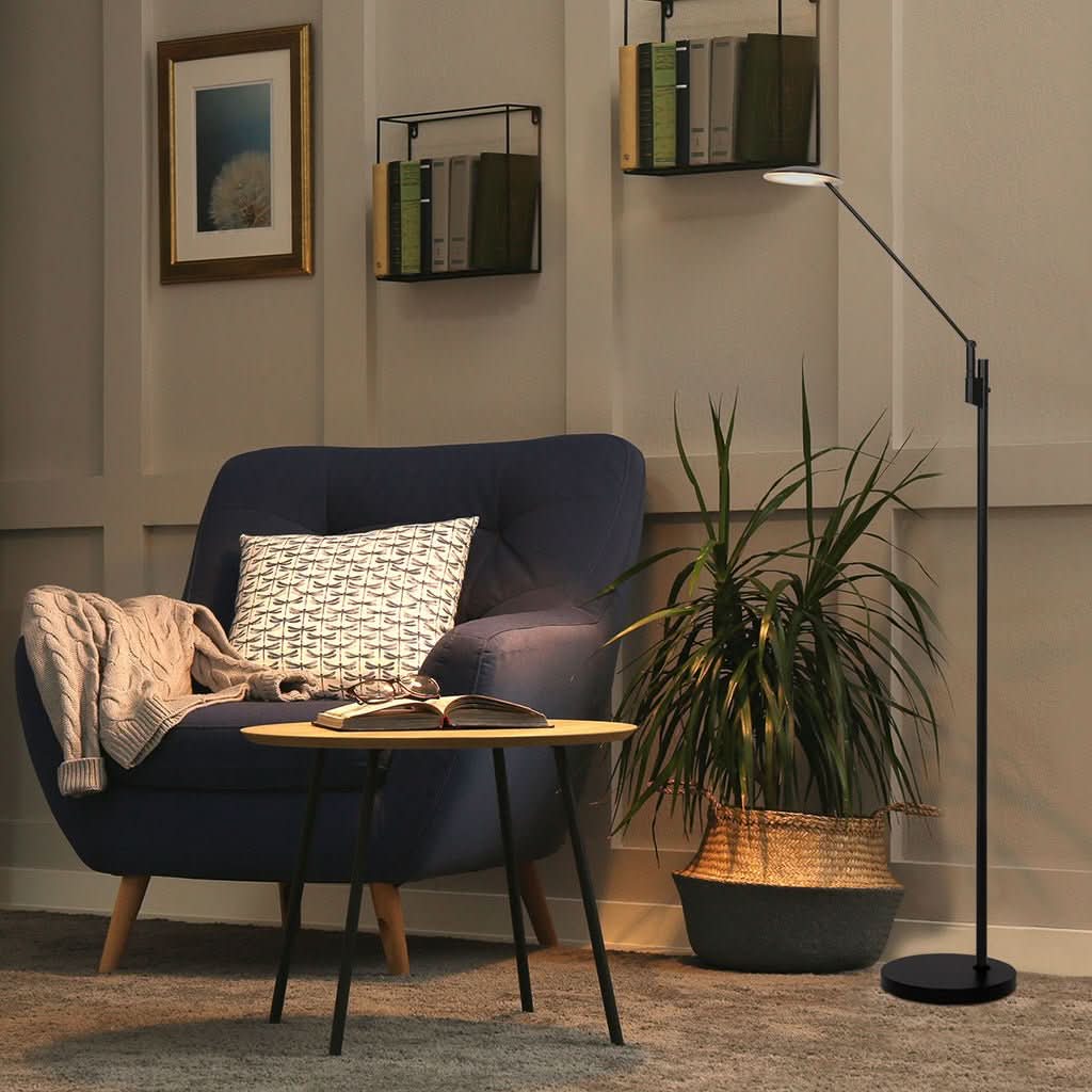 Mise en ambiance dans un salon, lampe allumée près d'un fauteuil bleu.