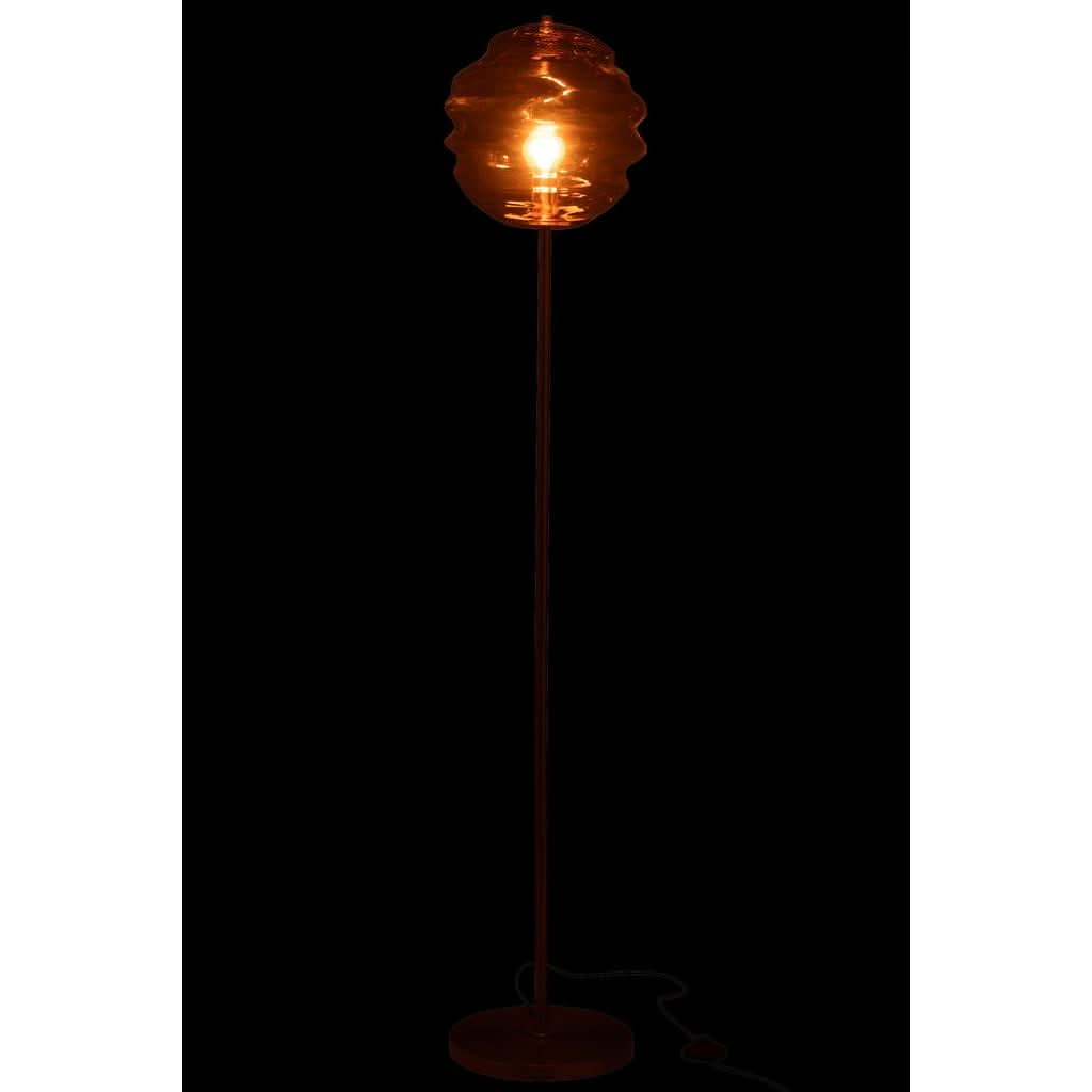 Lampe allumée sur fond noir, halo orangé traversant le verre ambré et la tige.