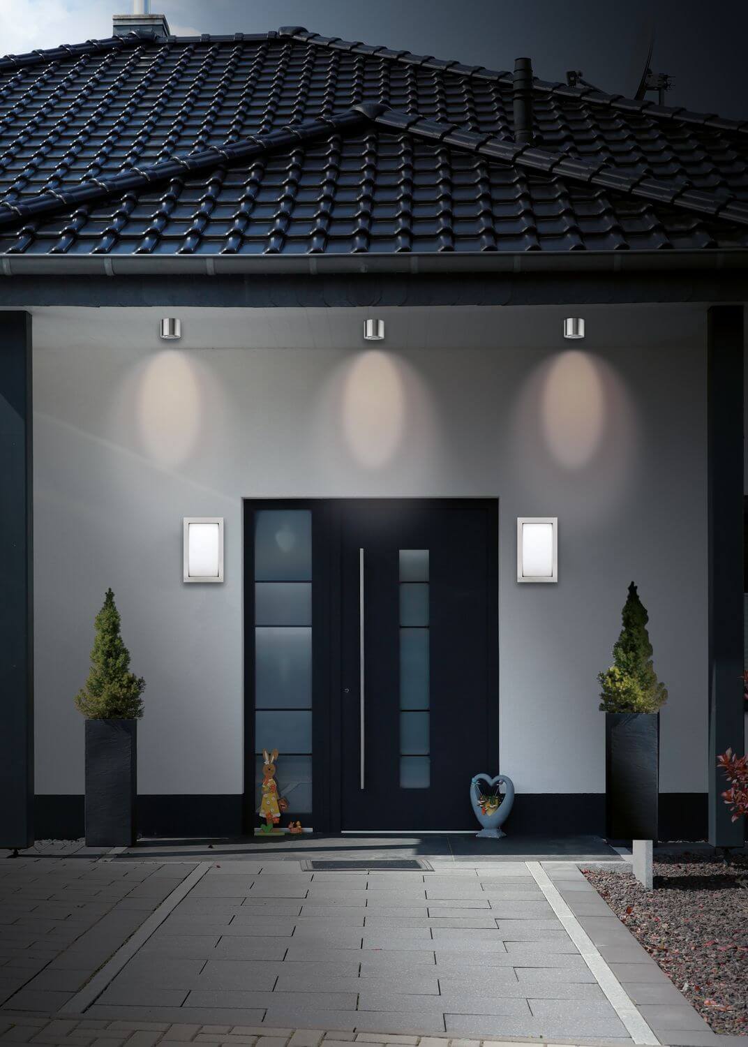 Plan rapproché de la façade avec les deux appliques rectangulaires en inox près de la porte