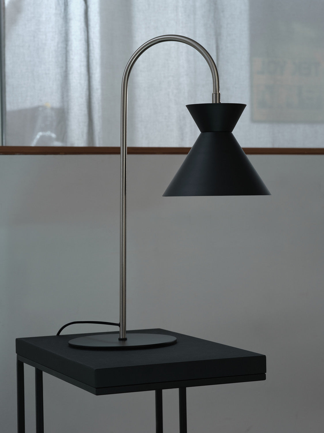 Vue rapprochée du luminaire sur une table noire, soulignant sa silhouette.