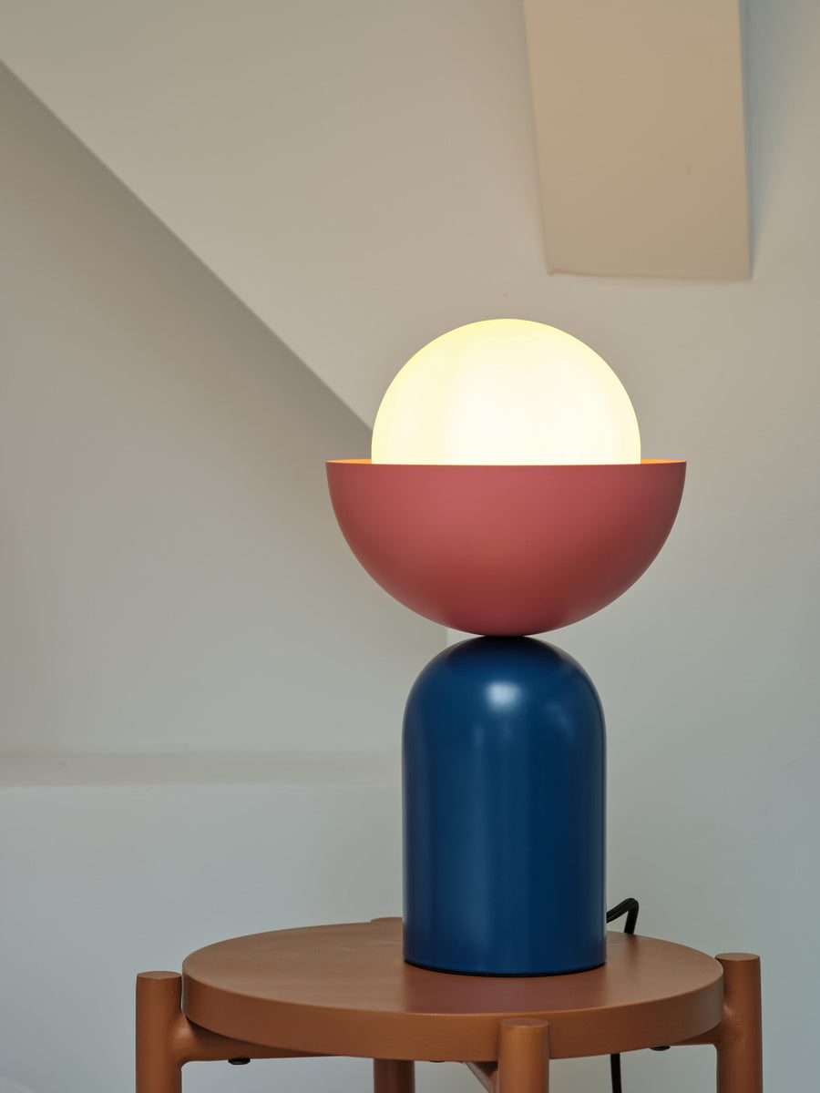 Lampe éclairée sur une table basse, montrant la lumière chaude et la silhouette.