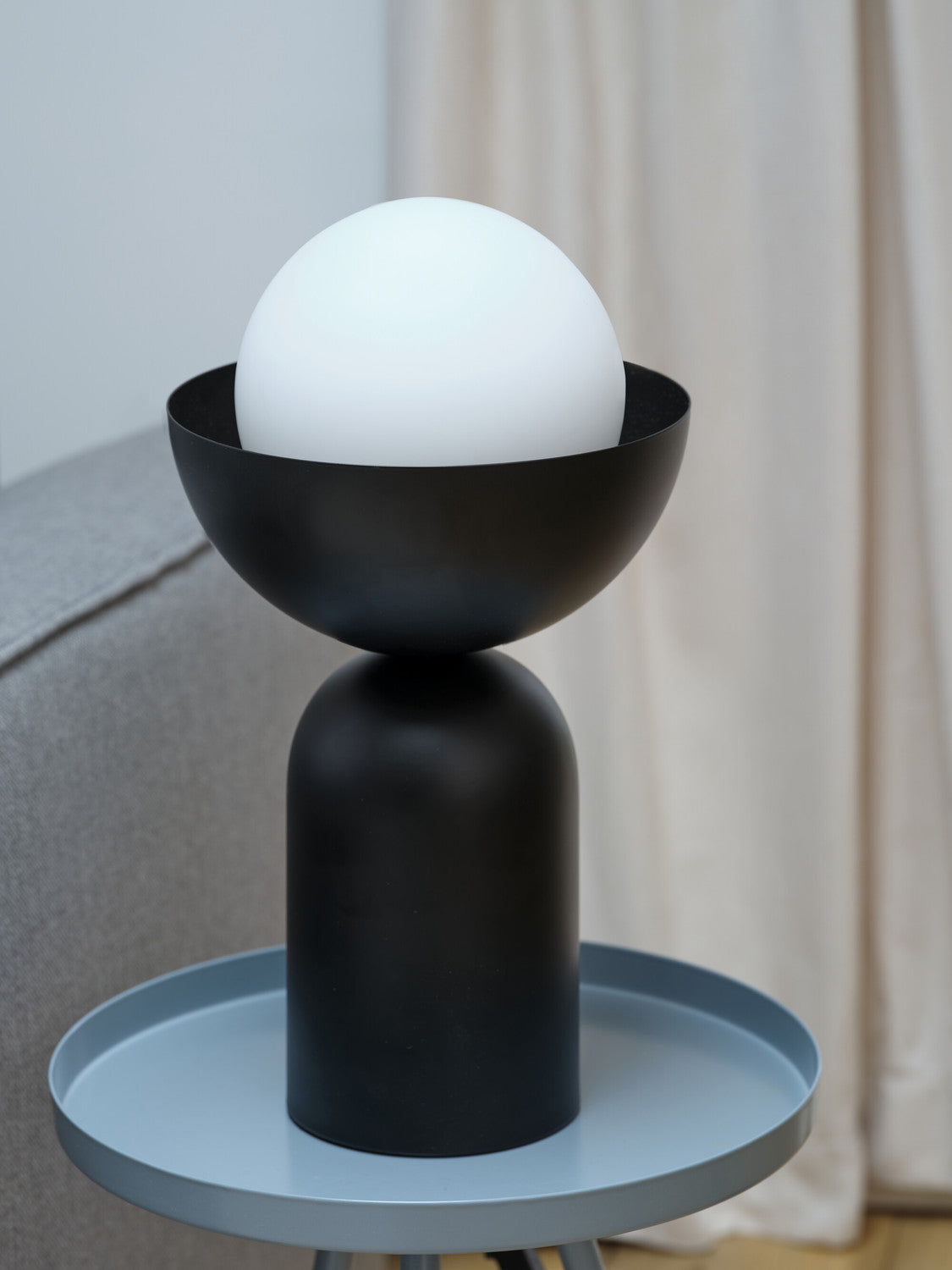 Gros plan de la lampe noire non allumée sur un plateau bleu clair.