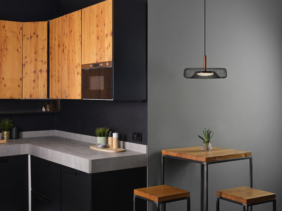 Suspension noire installée dans une cuisine contemporaine au-dessus d'un tabouret en bois.