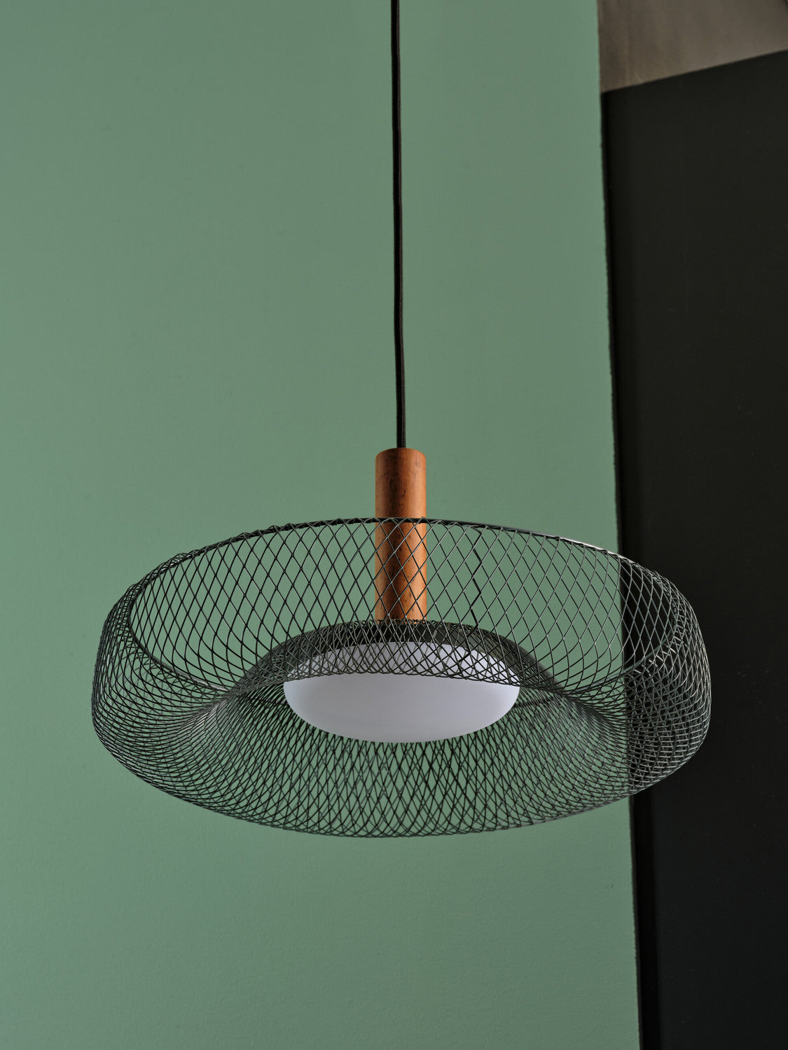 Détail de l'abat-jour en maille noire et du support central en bois.