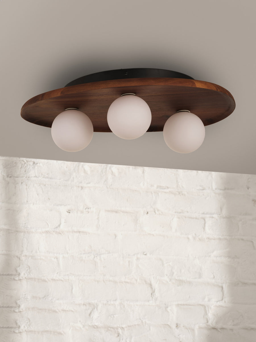 Vue rapprochée du luminaire fixé au plafond devant un mur en briques blanches.