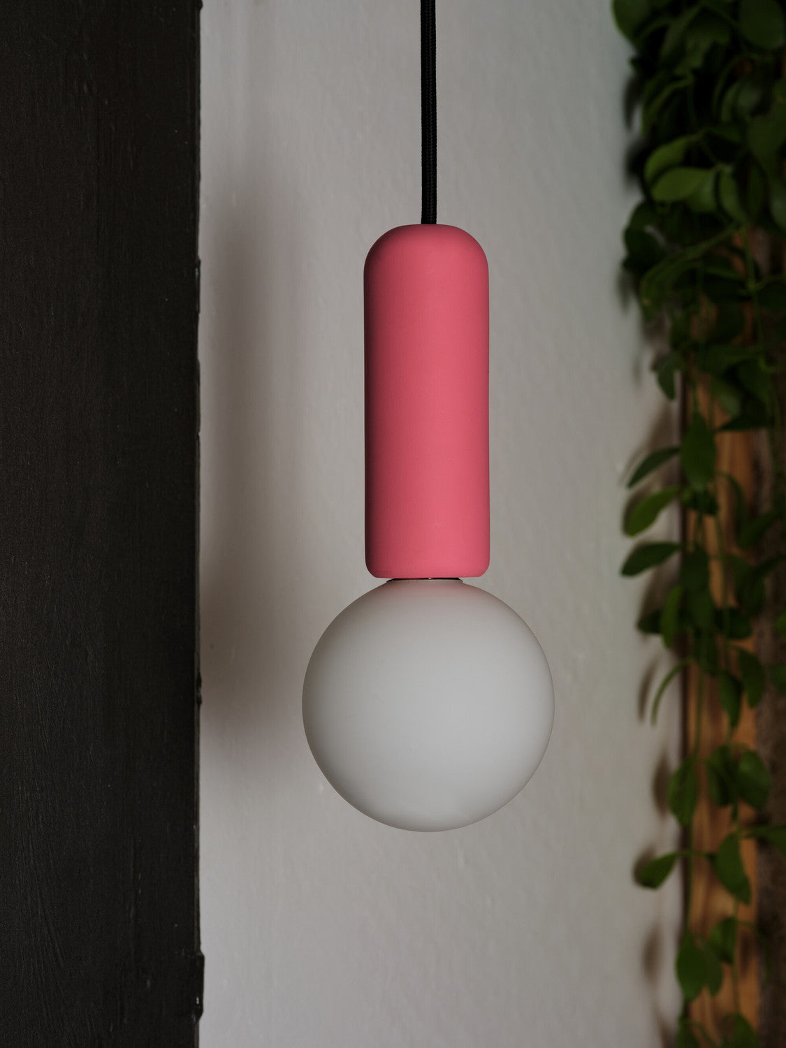 Gros plan sur le cylindre en béton rose et la sphère en verre blanc éteinte.