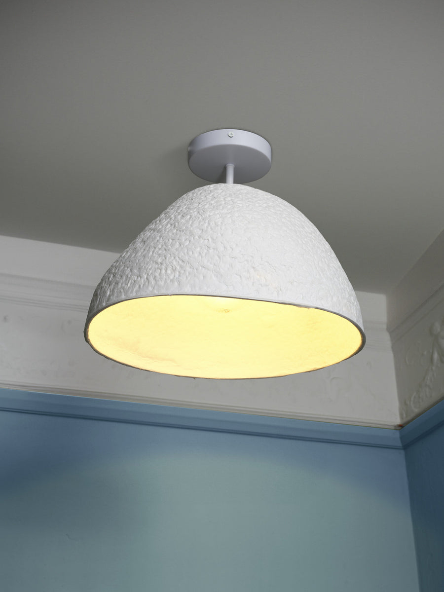Vue rapprochée du plafonnier allumé, mettant en valeur la texture et la lumière chaude.