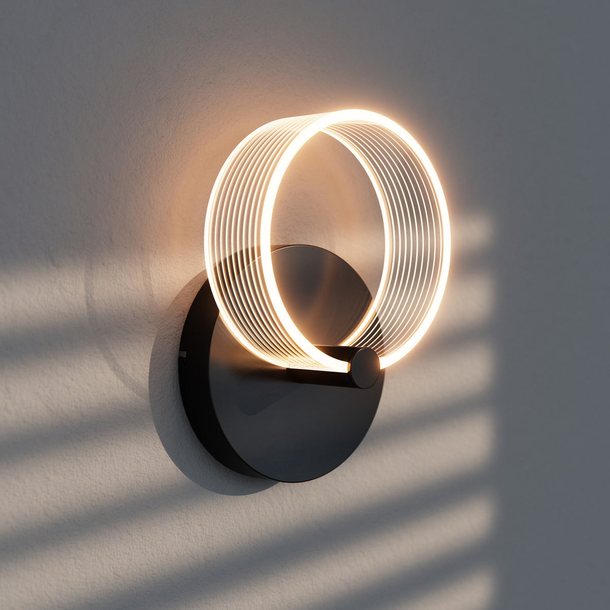 Gros plan de l'applique allumée sur mur gris, ombres striées et halo lumineux chaud.
