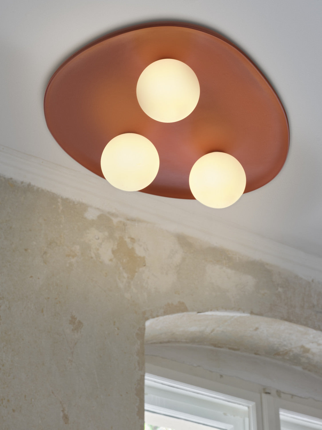 Gros plan du plafonnier terracotta et de ses trois globes lumineux