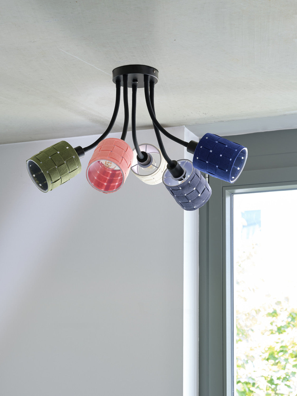 Détail du plafonnier sous plafond, abat-jours colorés et ampoules visibles près d’une fenêtre.
