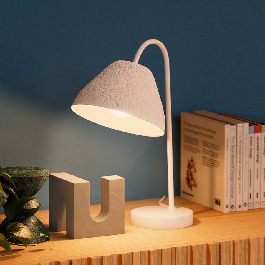 Gros plan de la lampe allumée sur une étagère en bois, mur bleu et livres.