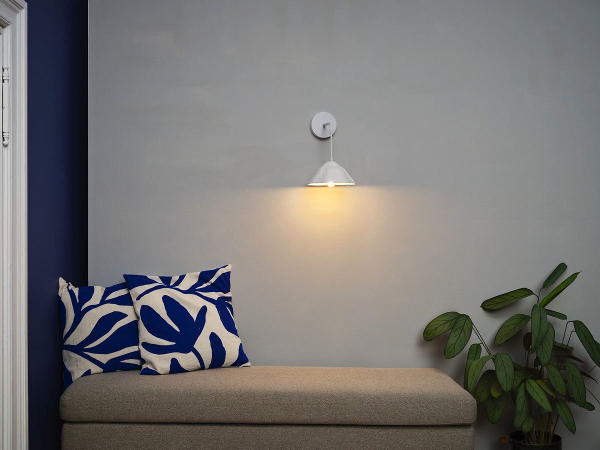 Mise en ambiance au-dessus d'un banc, mur gris et coussins bleu vif