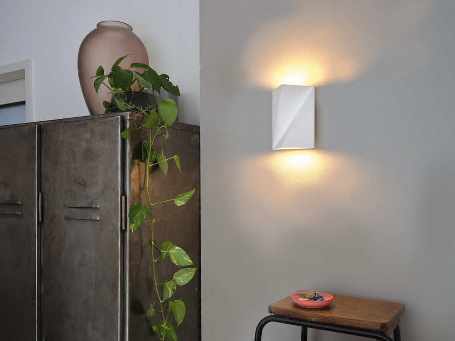 Applique murale fixée sur un mur gris, éclairant vers le haut et le bas.