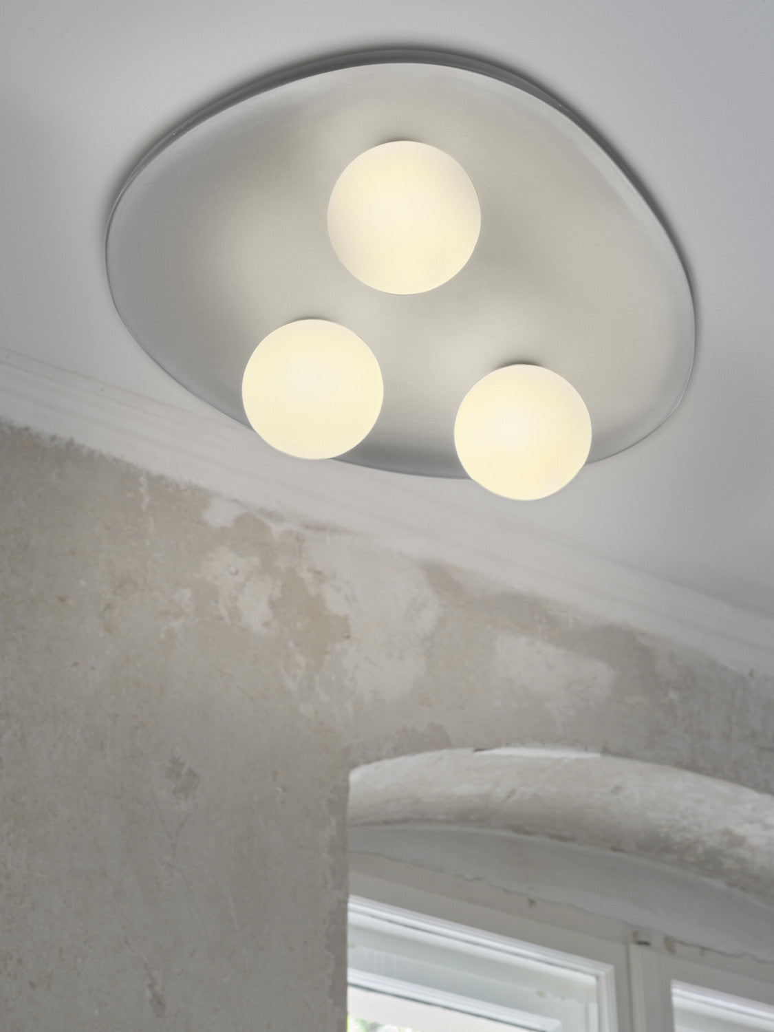 Détail de près sous plafond, trois globes lumineux et finition plâtre blanc