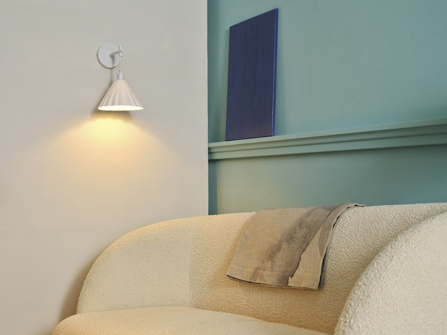 Applique blanche allumée au-dessus d'un canapé beige dans un salon