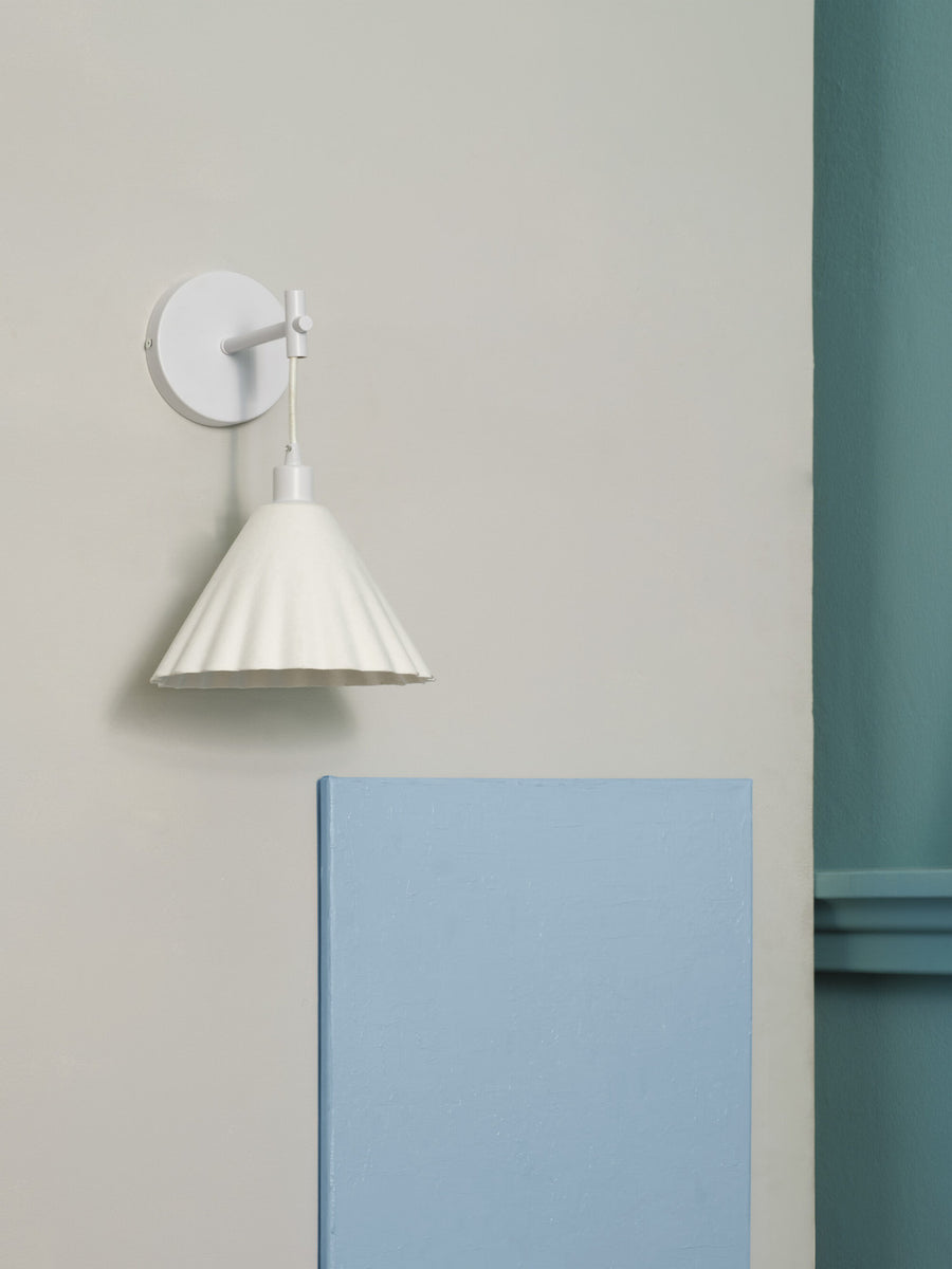 Vue de profil de l'applique blanche fixée sur un mur clair